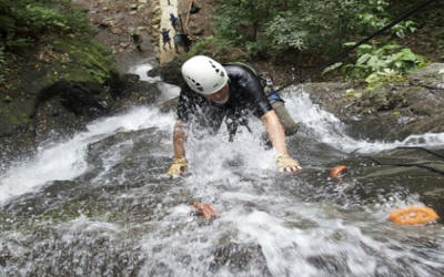 Adventurer rappelling down waterfall cliff in Costa Rican rainforest with safety equipment and guides - Macaws Adventure Tours by Pablo C